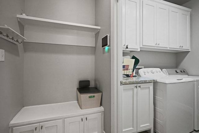 clothes washing area featuring cabinets and separate washer and dryer