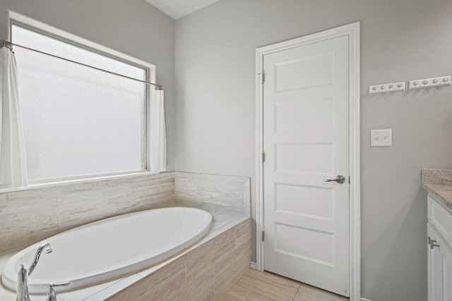 bathroom featuring vanity and tiled bath