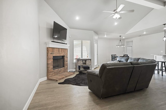 living room with wood-type flooring, high vaulted ceiling, beamed ceiling, ceiling fan, and a fireplace