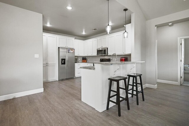 kitchen featuring hanging light fixtures, a kitchen breakfast bar, stainless steel appliances, white cabinets, and kitchen peninsula