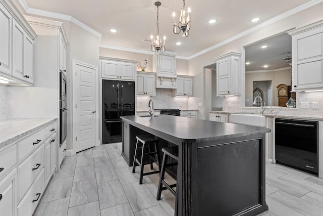 kitchen featuring decorative backsplash, black appliances, an island with sink, and a breakfast bar