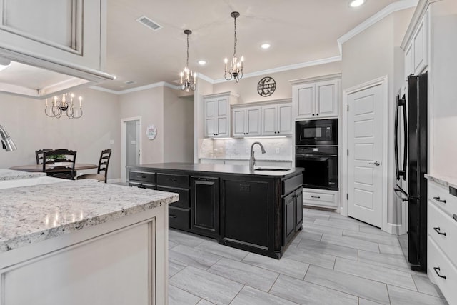 kitchen featuring white cabinetry, an island with sink, sink, a chandelier, and black appliances