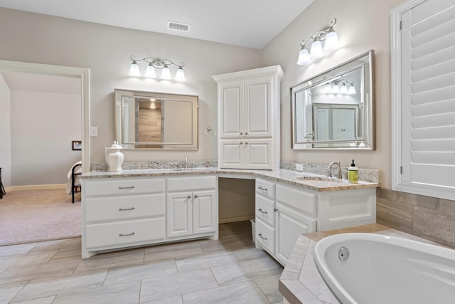 bathroom featuring vanity and tiled tub