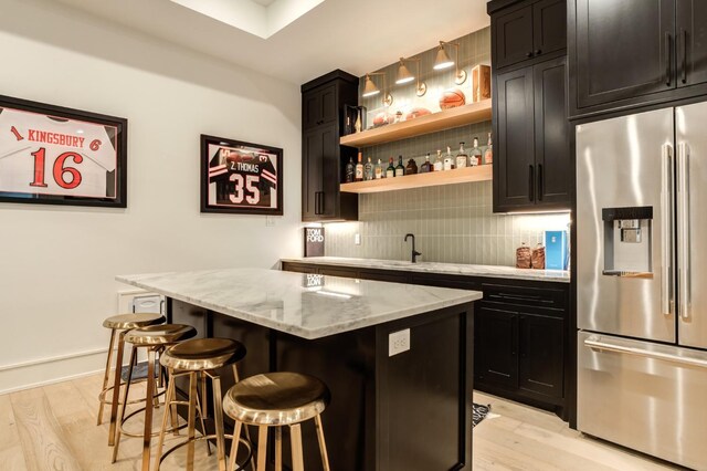 7722 47th St, Lubbock, TX 79407 - indoor wet bar with stainless steel fridge, light wood-style flooring, and decorative backsplash