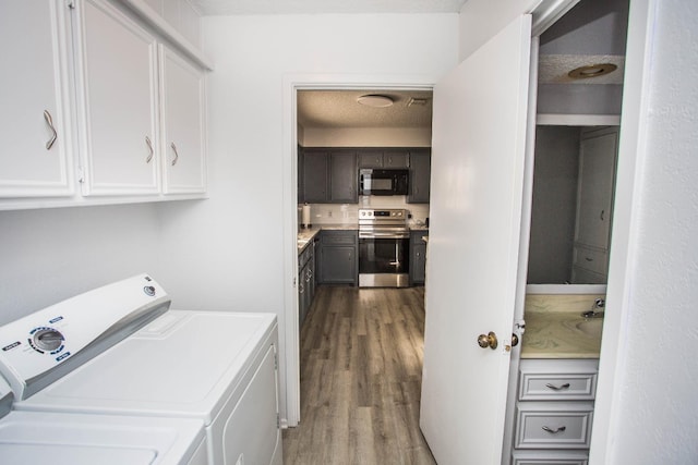 laundry area with cabinets, washing machine and dryer, hardwood / wood-style floors, and a textured ceiling