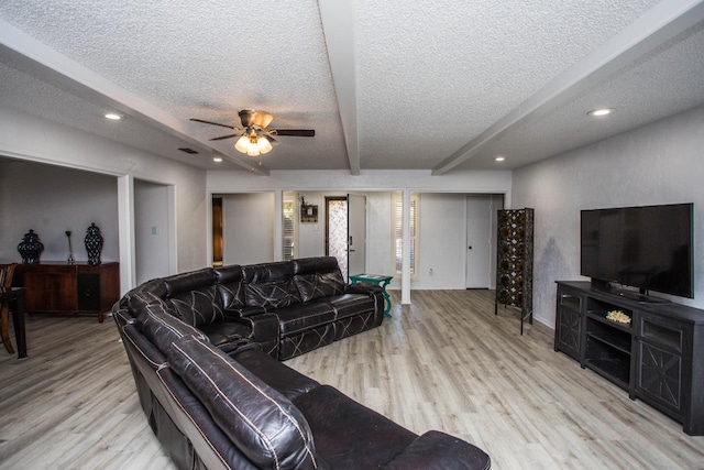 living room featuring beamed ceiling, ceiling fan, a textured ceiling, and light wood-type flooring