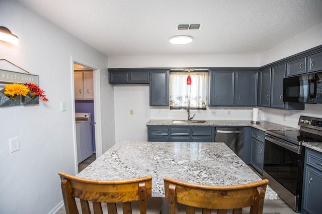 kitchen featuring appliances with stainless steel finishes, sink, a textured ceiling, and light stone counters