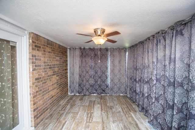 empty room with ceiling fan, wood-type flooring, and a textured ceiling