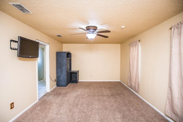 carpeted spare room featuring a textured ceiling and ceiling fan