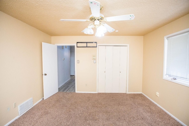 unfurnished bedroom with ceiling fan, carpet floors, a textured ceiling, and a closet