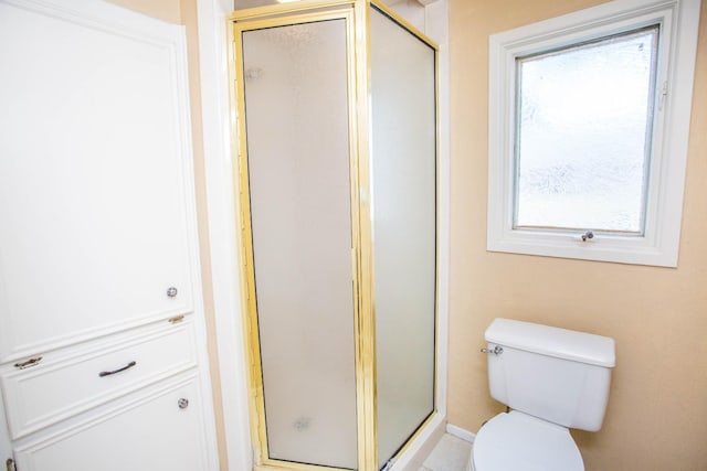 bathroom featuring a shower with door and toilet