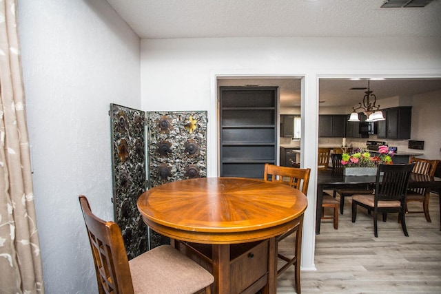 dining space with light hardwood / wood-style floors and a textured ceiling