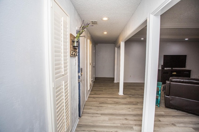 hall with light hardwood / wood-style flooring and a textured ceiling