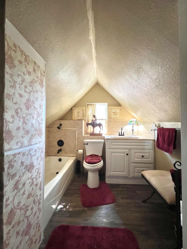 bathroom featuring hardwood / wood-style floors, a textured ceiling, vaulted ceiling, a tub, and toilet