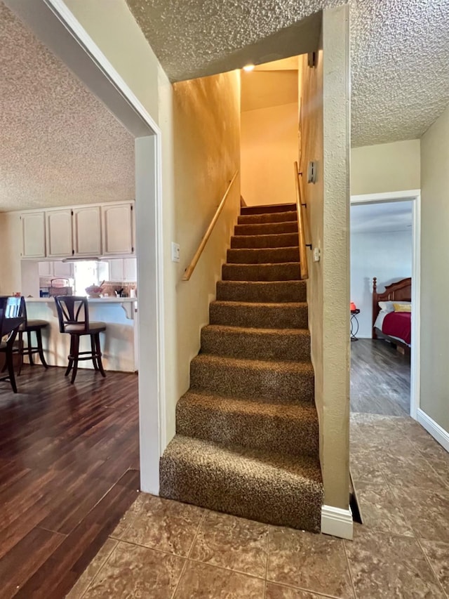 stairs with wood-type flooring and a textured ceiling