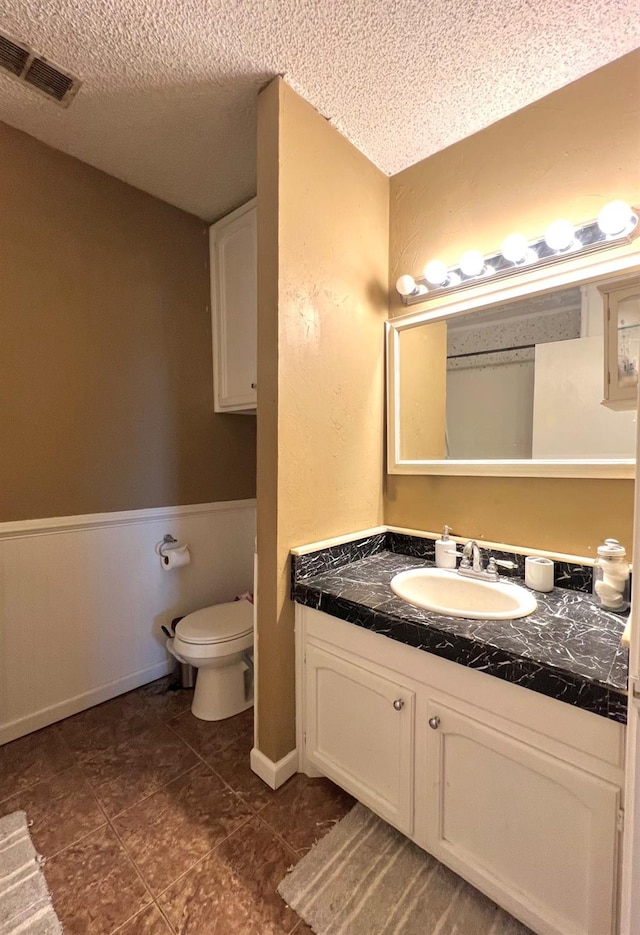 bathroom with vanity, toilet, and a textured ceiling