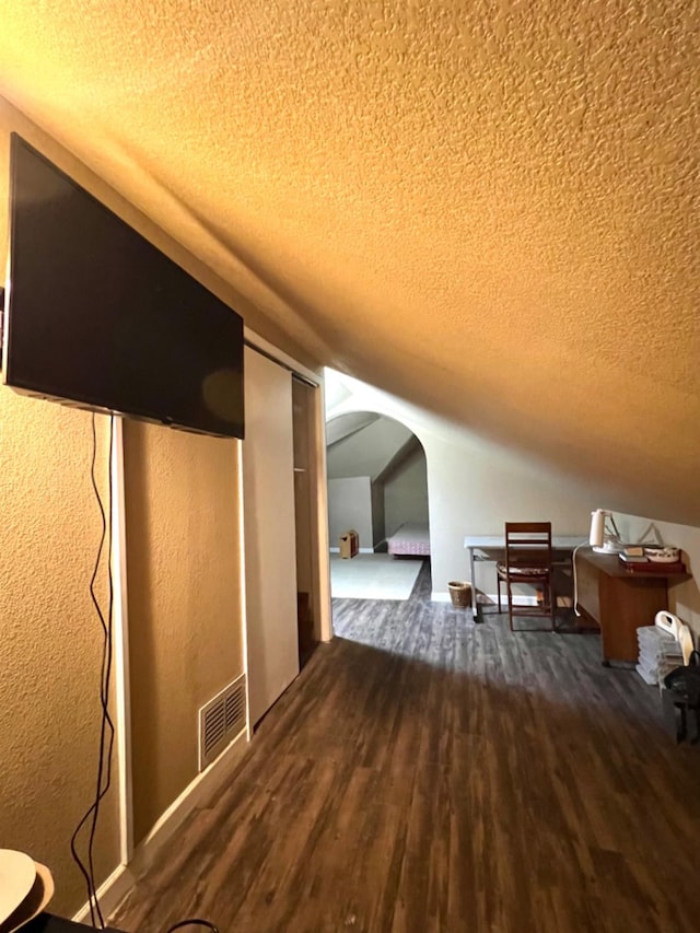 bonus room featuring dark hardwood / wood-style flooring, vaulted ceiling, and a textured ceiling