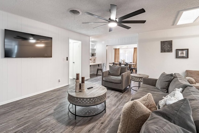 living room with hardwood / wood-style flooring, ceiling fan, and a textured ceiling