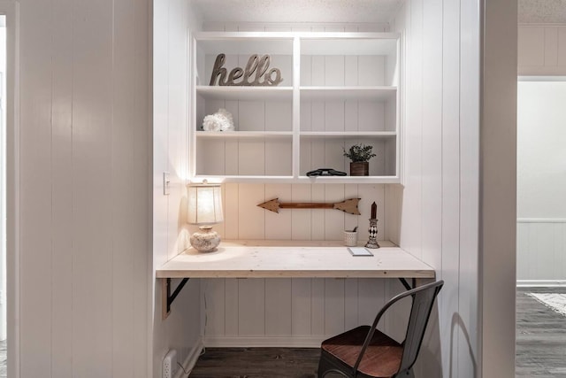 office with built in shelves, dark wood-type flooring, and a textured ceiling