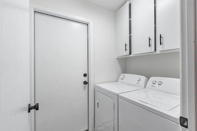 clothes washing area featuring cabinets and separate washer and dryer