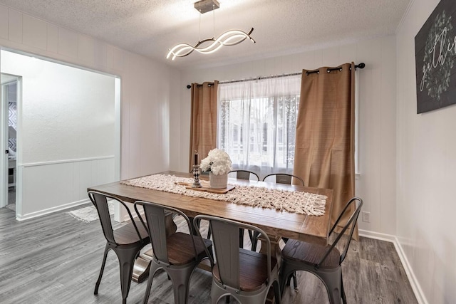 dining room featuring an inviting chandelier, hardwood / wood-style floors, and a textured ceiling