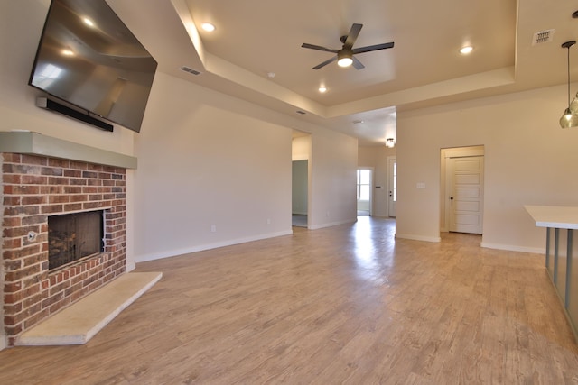 10504 Ave X, Lubbock, TX 79423 - unfurnished living room featuring a raised ceiling, ceiling fan, a fireplace, light wood finished floors, and recessed lighting