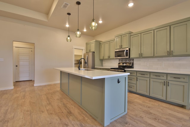 10504 Ave X, Lubbock, TX 79423 - kitchen featuring stainless steel appliances, decorative backsplash, a kitchen island with sink, light countertops, and pendant lighting