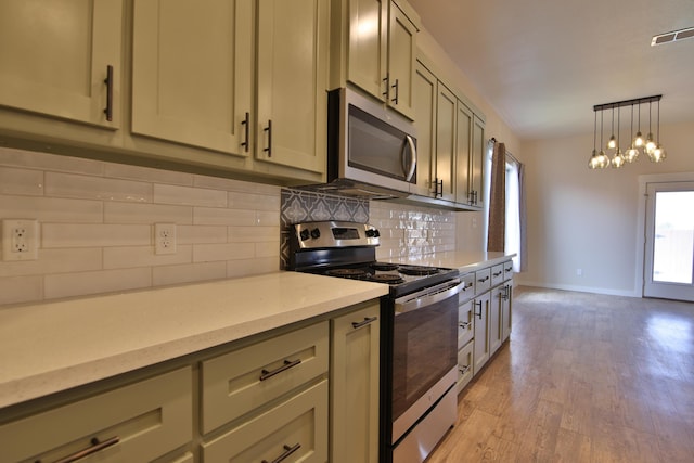 10504 Ave X, Lubbock, TX 79423 - kitchen with appliances with stainless steel finishes, light countertops, tasteful backsplash, light wood finished floors, and decorative light fixtures