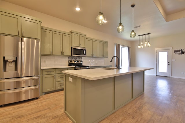 10504 Ave X, Lubbock, TX 79423 - kitchen featuring stainless steel appliances, decorative backsplash, light countertops, a center island with sink, and light wood-type flooring