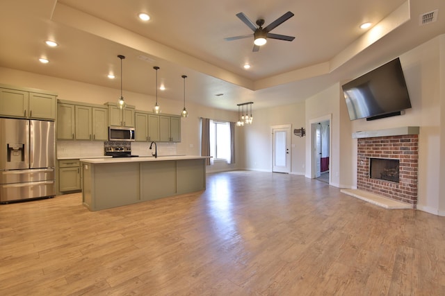 10504 Ave X, Lubbock, TX 79423 - kitchen with appliances with stainless steel finishes, open floor plan, a ceiling fan, light countertops, and a brick fireplace