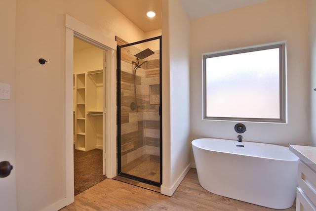 10504 Ave X, Lubbock, TX 79423 - full bathroom featuring a shower stall, a walk in closet, a freestanding tub, and wood finished floors
