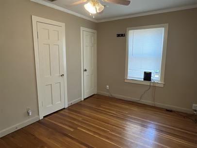 unfurnished bedroom featuring dark wood-type flooring, ceiling fan, and crown molding