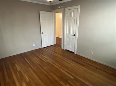 unfurnished bedroom featuring crown molding and dark hardwood / wood-style floors