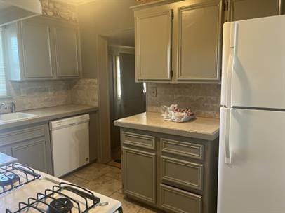 kitchen with tasteful backsplash, sink, gray cabinetry, and white appliances