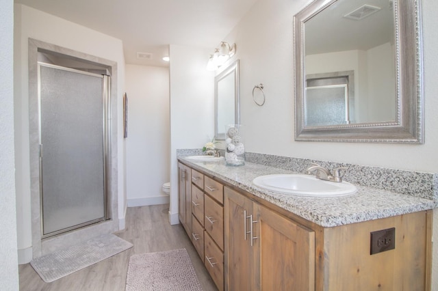 bathroom with vanity, toilet, an enclosed shower, and wood-type flooring