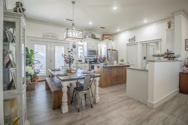 dining space with crown molding and light wood-type flooring