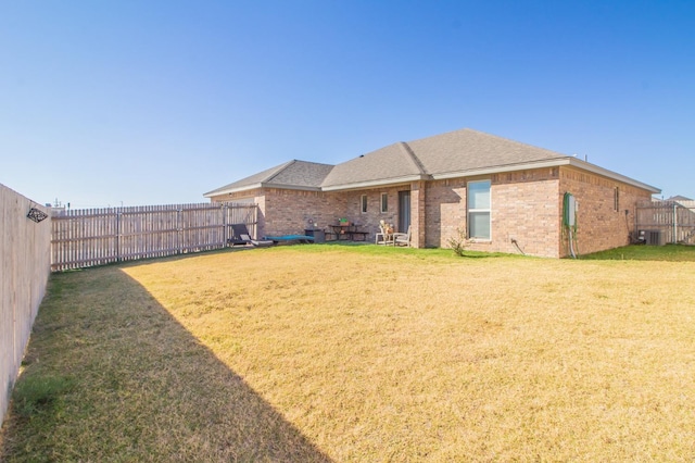 rear view of property featuring a lawn and central air condition unit