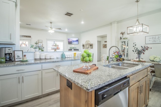 kitchen featuring pendant lighting, white cabinetry, sink, stainless steel dishwasher, and a center island with sink