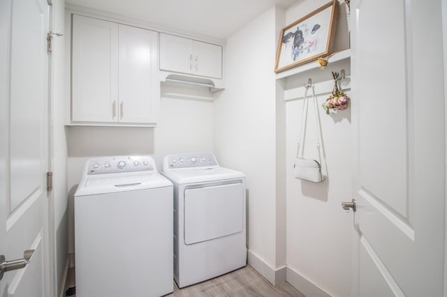 laundry room with cabinets, washer and dryer, and light wood-type flooring