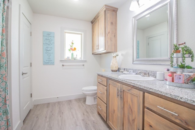 bathroom featuring vanity, wood-type flooring, and toilet