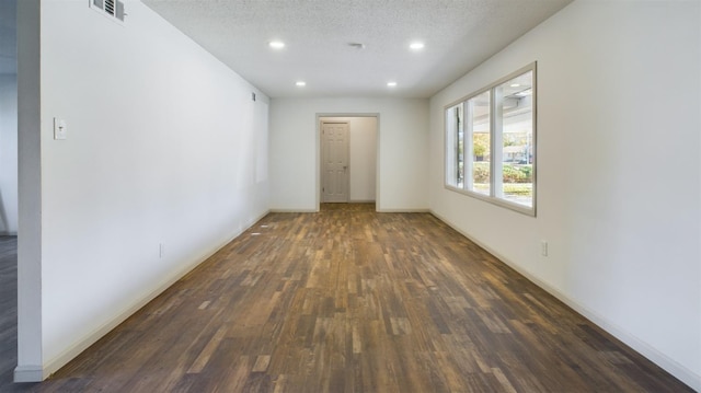 empty room with dark wood-type flooring and a textured ceiling