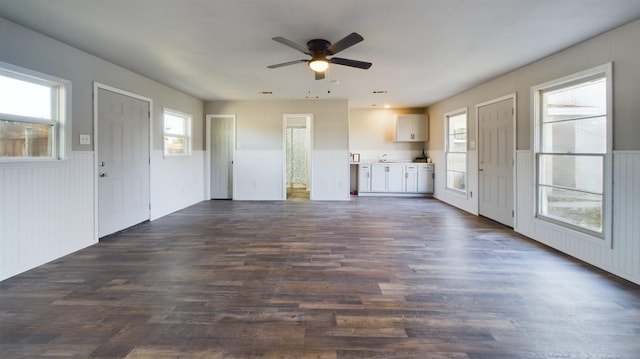 unfurnished living room with a wealth of natural light, dark hardwood / wood-style floors, and ceiling fan