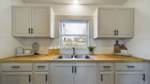 kitchen featuring wood counters, sink, backsplash, and gray cabinets