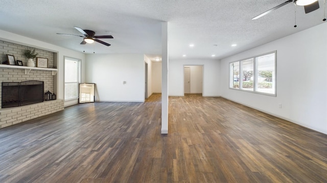 unfurnished living room with dark hardwood / wood-style flooring, ceiling fan, a fireplace, and a textured ceiling