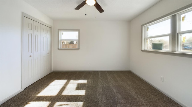 unfurnished bedroom featuring dark carpet, ceiling fan, and a closet