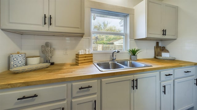 kitchen with tasteful backsplash, butcher block countertops, and sink