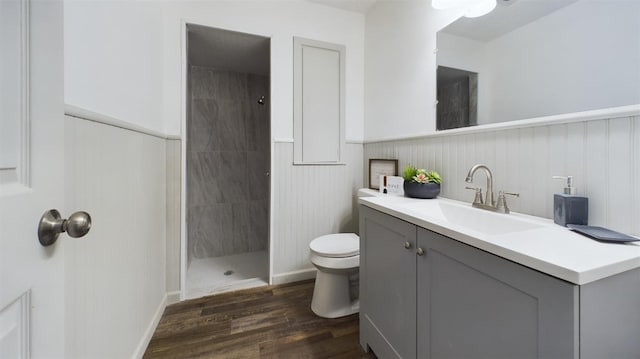 bathroom featuring tiled shower, wood-type flooring, toilet, and vanity