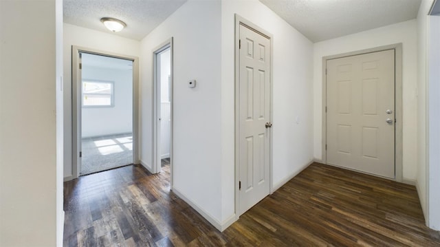 hallway with dark hardwood / wood-style floors and a textured ceiling