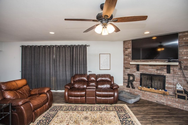 living room with a brick fireplace, wood-type flooring, and ceiling fan