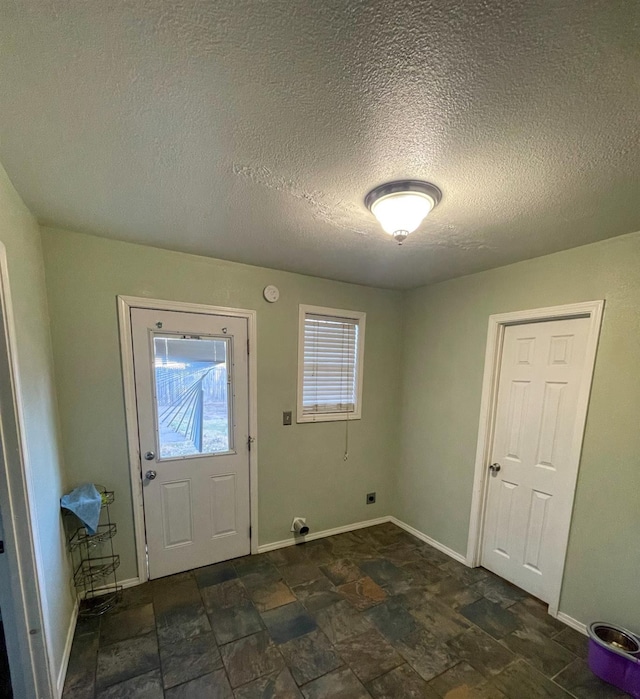 entryway featuring stone finish floor and baseboards